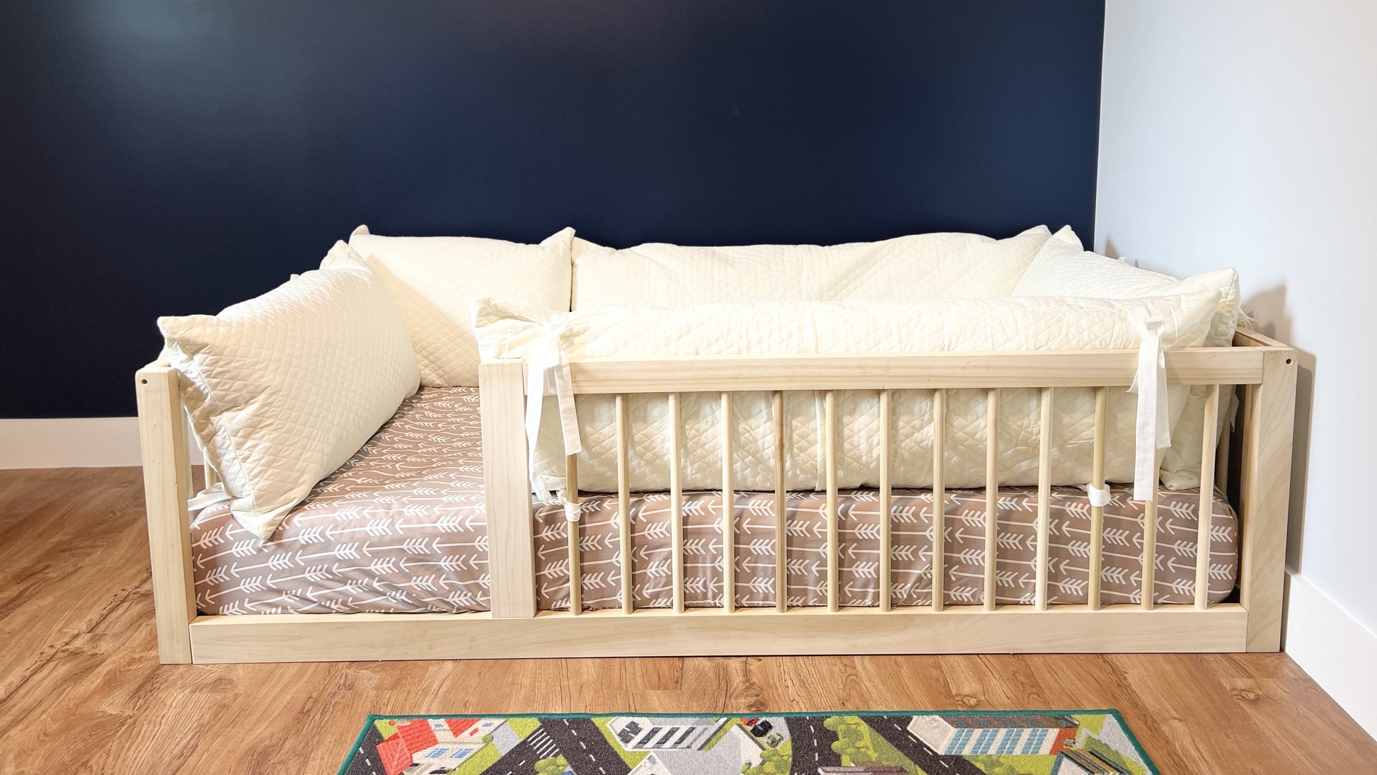 Montesorri floor bed with white pillows surrounding the matress
