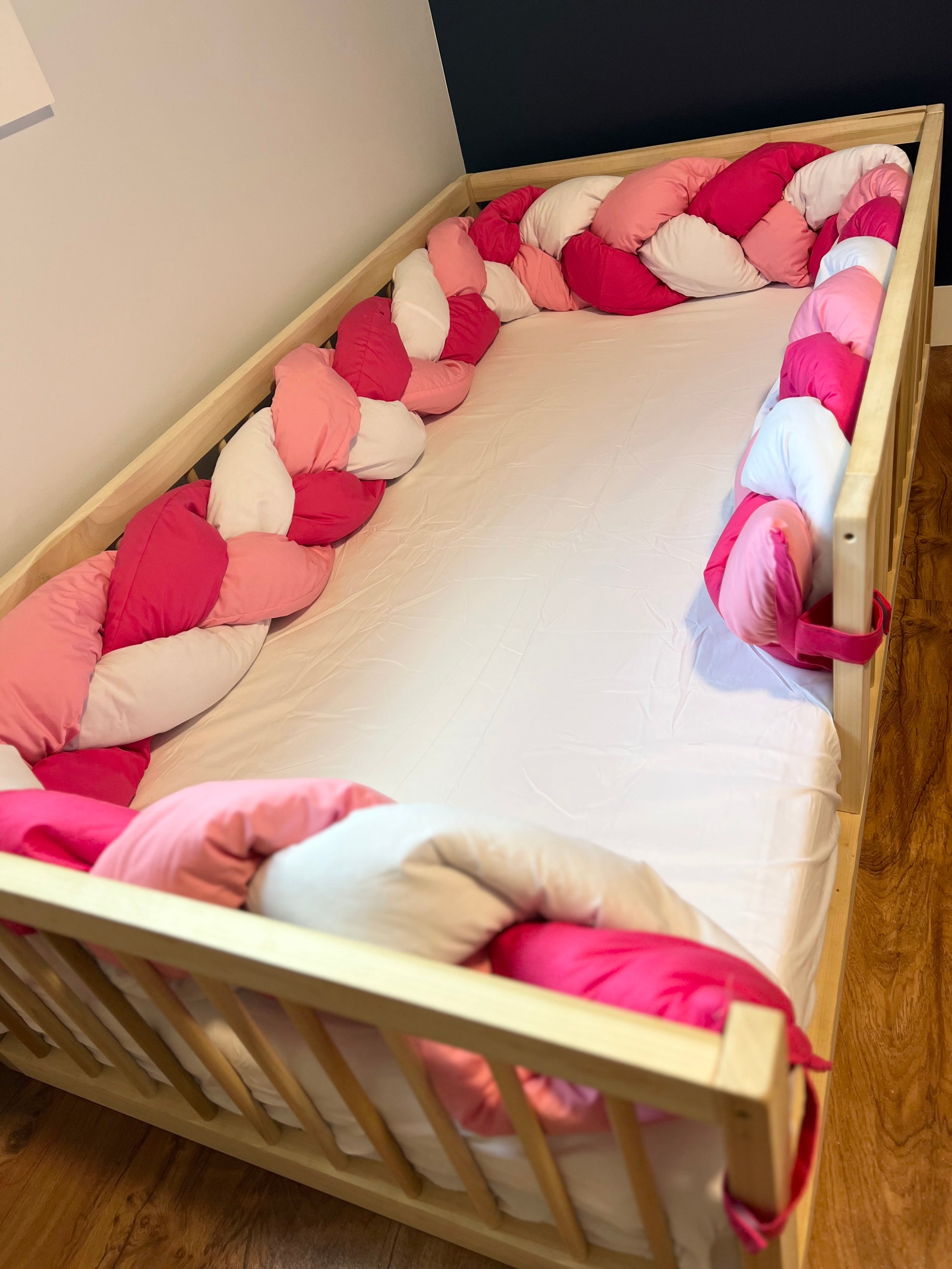 Non-toxic Montessori Floor Bed with pink and white bumper pillow.